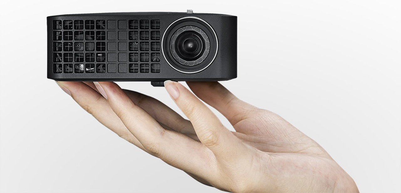 A hand holding the Dell M318WL projector between its fingertips