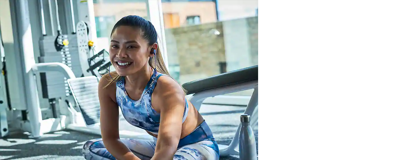 A girl wears JBL REFLECT MINI 2 Lightweight Wireless Sport Headphones