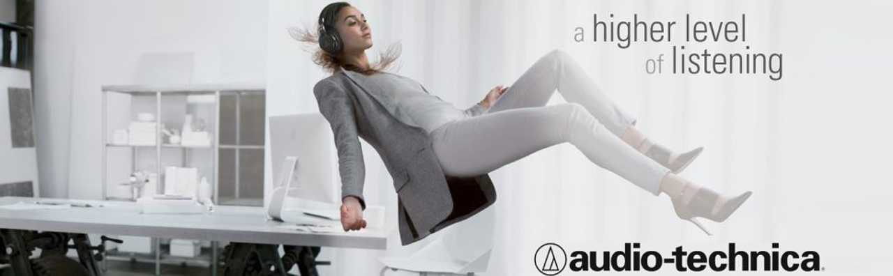 Audio-Technica Banner Showing a Female Office Worker Floating Off Her Desk Wearing Headphones. There Is Text That Reads: A Higher Level of Listening