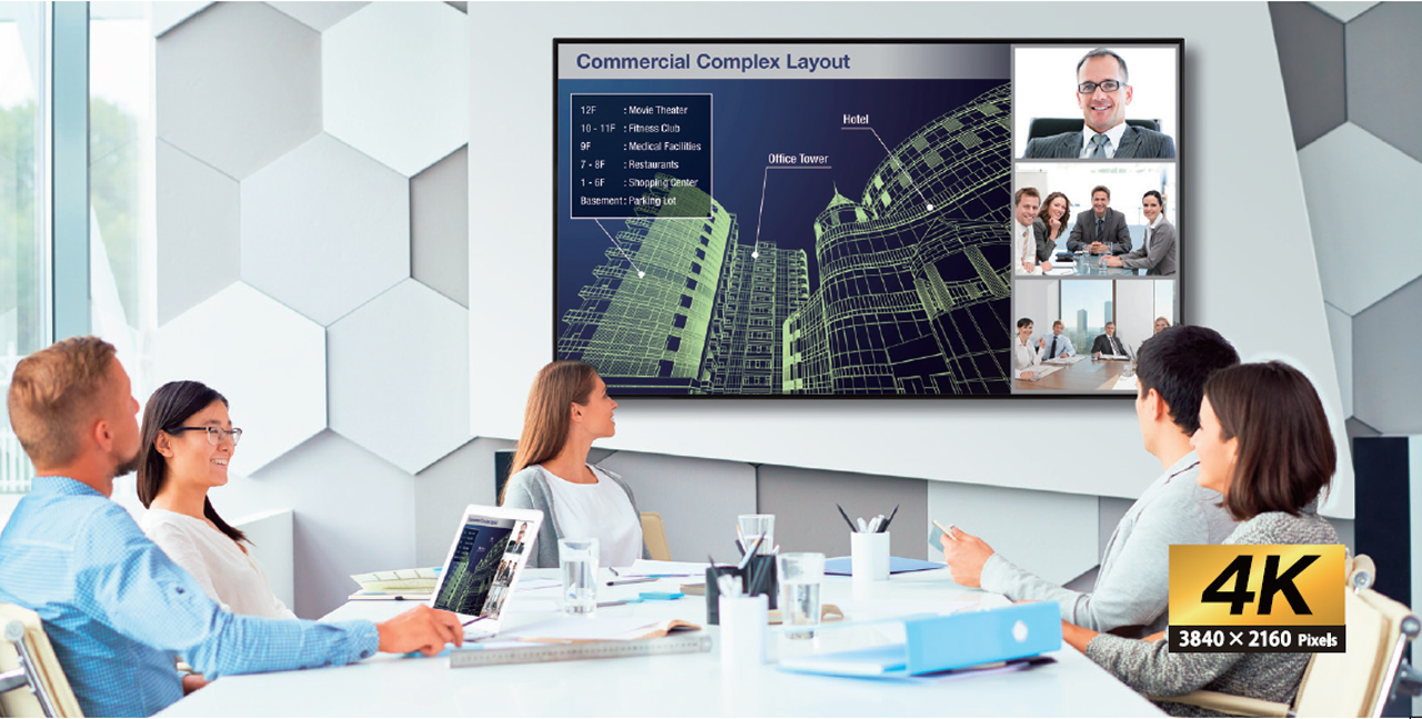A mounted Sharp display in a conference room where a meeting is taking place about a commercial complex layout plan