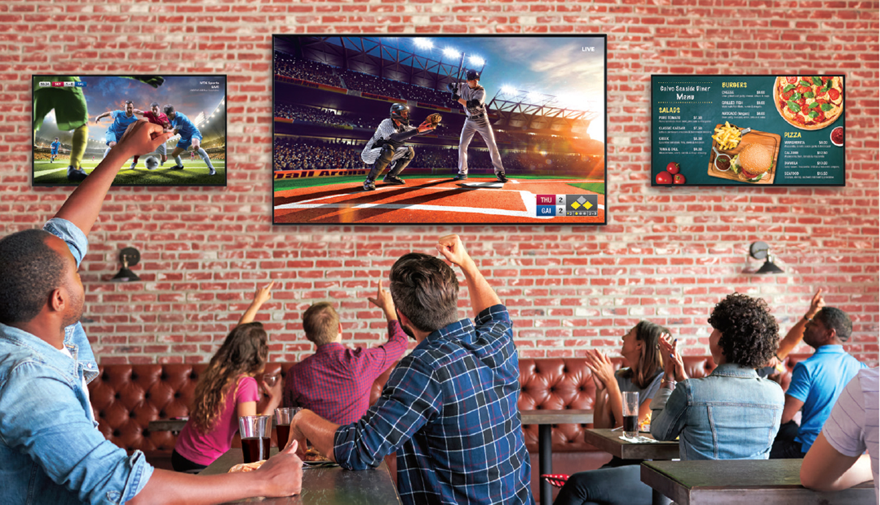 Three mounted Sharp displays showing sports and menu information for a sports bar where patrons are watching and cheering