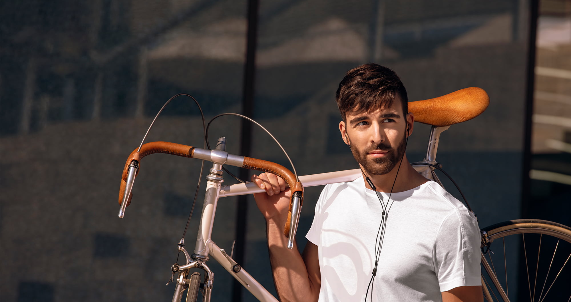 A man carrying his street bike over his right shoulder wearing beyerdynamic earbuds