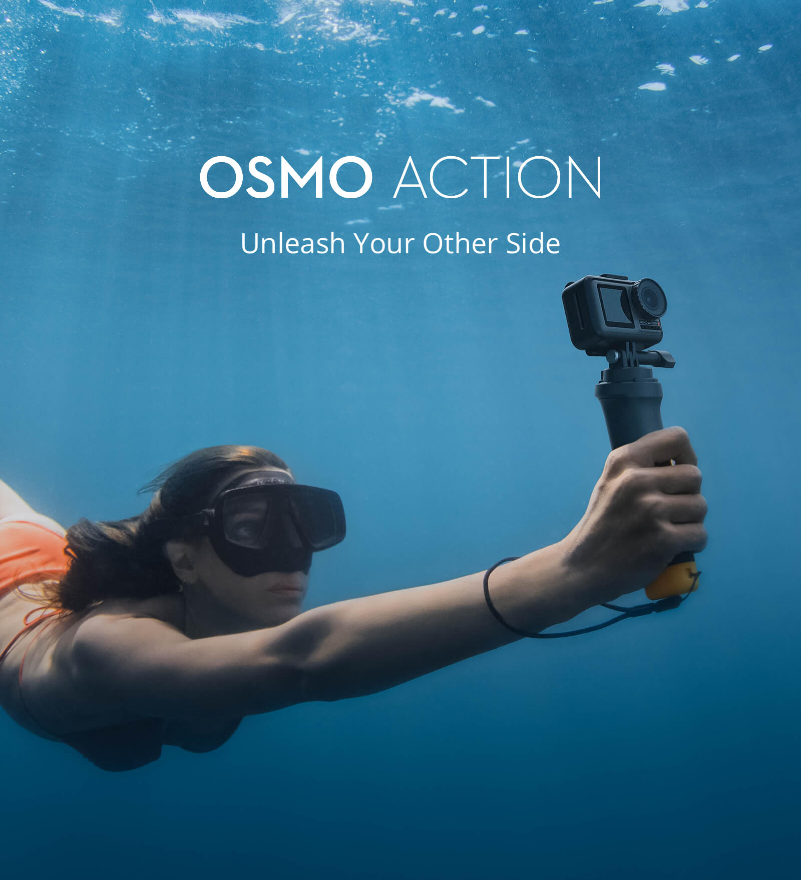 A Female Swimmer Underwater swimming through, taking a selfie holding the Osmo Action