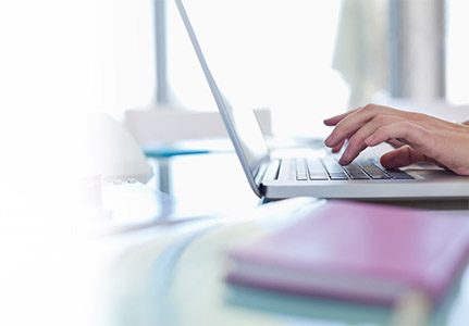 Hands typing on a laptop on a desk
