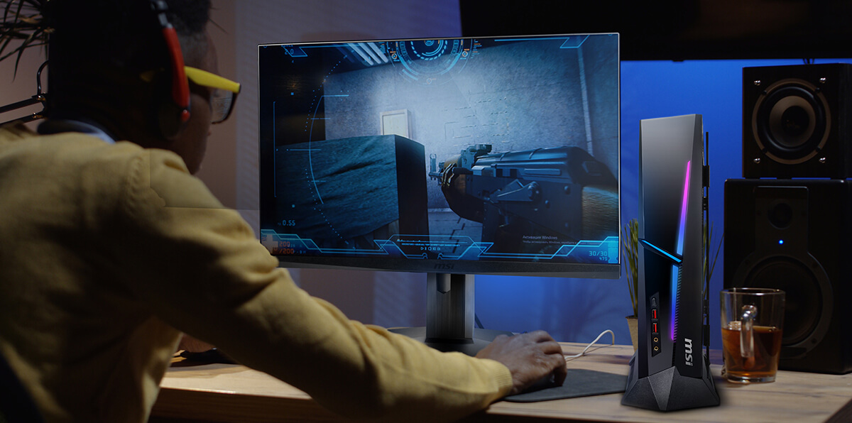 A man is gaming. The thin desktop pc next to monitor that saves spaces.