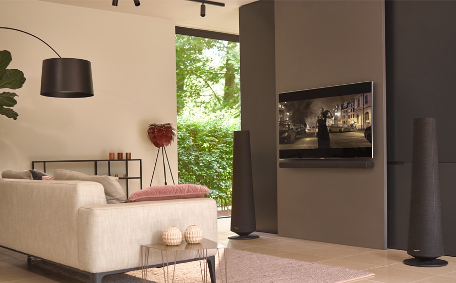 A modern living room with two black harman kardon citation towers next to a flat-screen TV