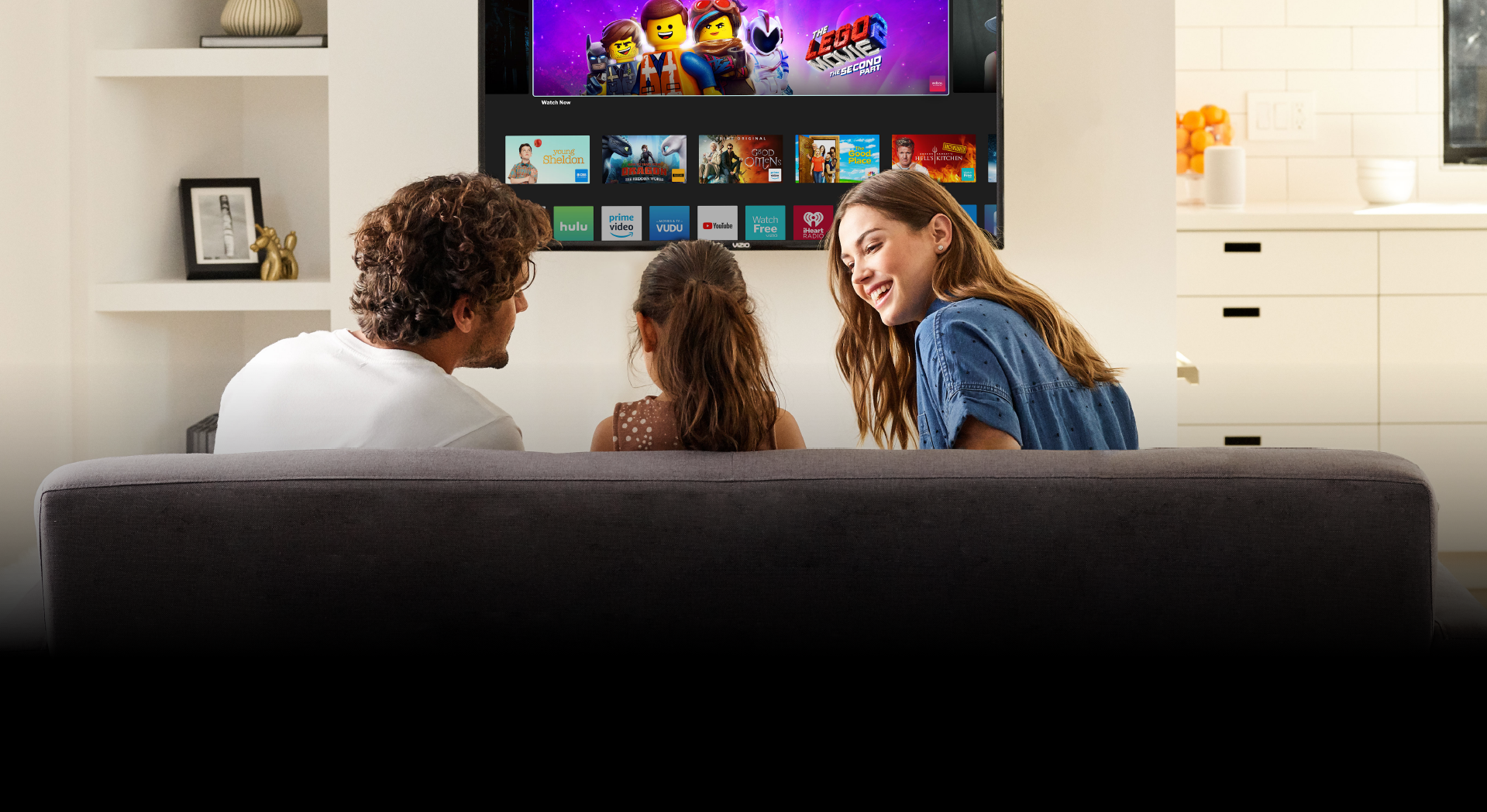 A family of three sitting on the couch watching the P759-G1 Smart TV