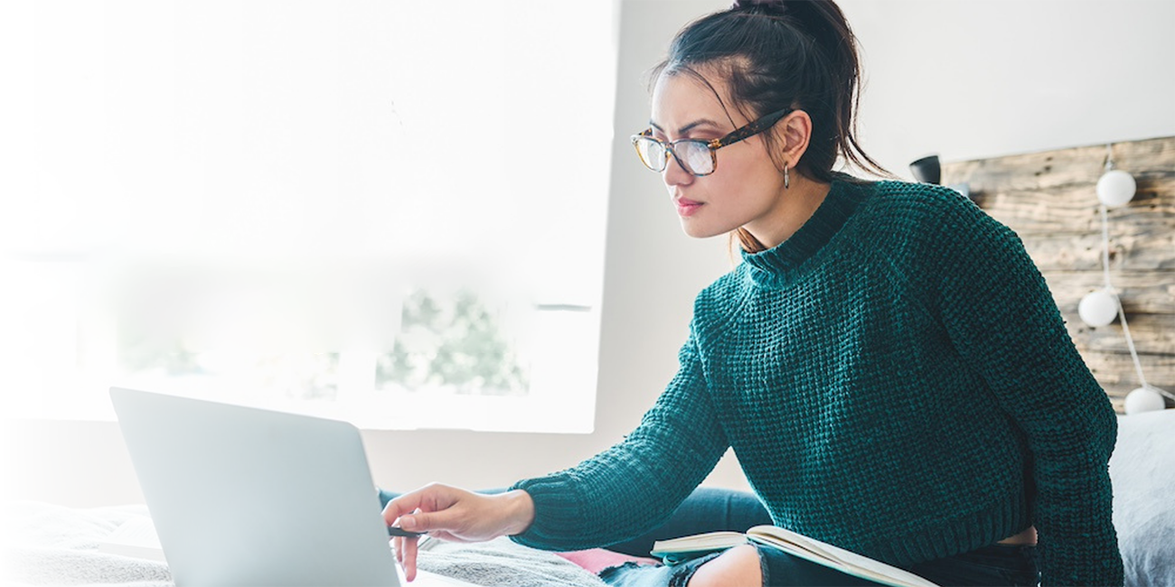 A woman is pointing at the screen of a laptop with a stylus.