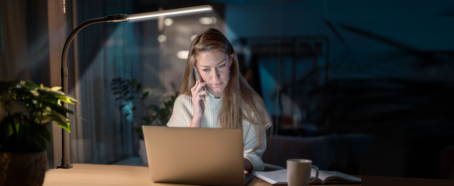 Indoor nighttime scene showing person working at laptop computer in dark room with dramatic lighting.