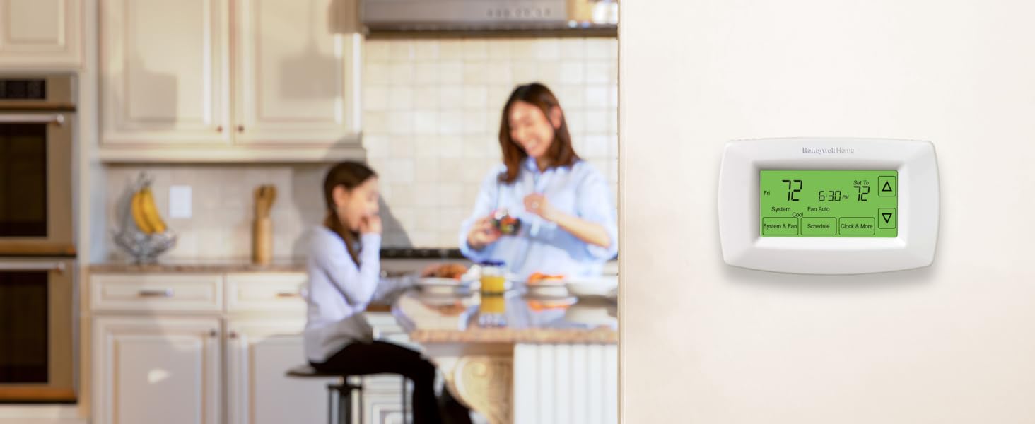 Mother and daughter in kitchen in background, thermostat on wall in foreground