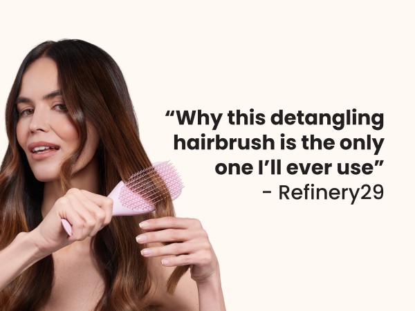 A woman brushing her hair with a pink ultimate detangler brush.