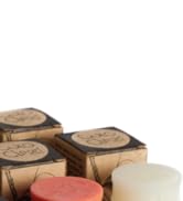 Wooden hexagonal containers with cork or wooden lids, displaying neutral-toned circular items including beige, cream, and coral-pink colored products.