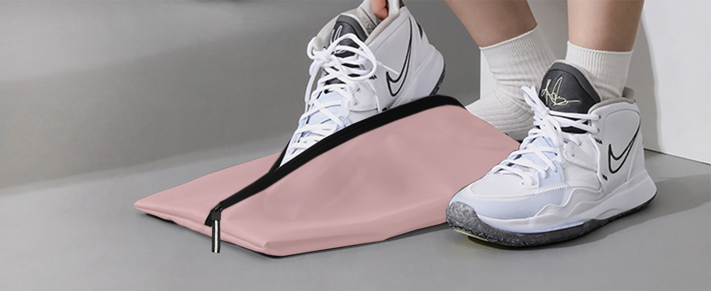 White Nike basketball shoes with gray soles, worn by a person. A pink yoga mat or exercise mat is visible in the foreground.