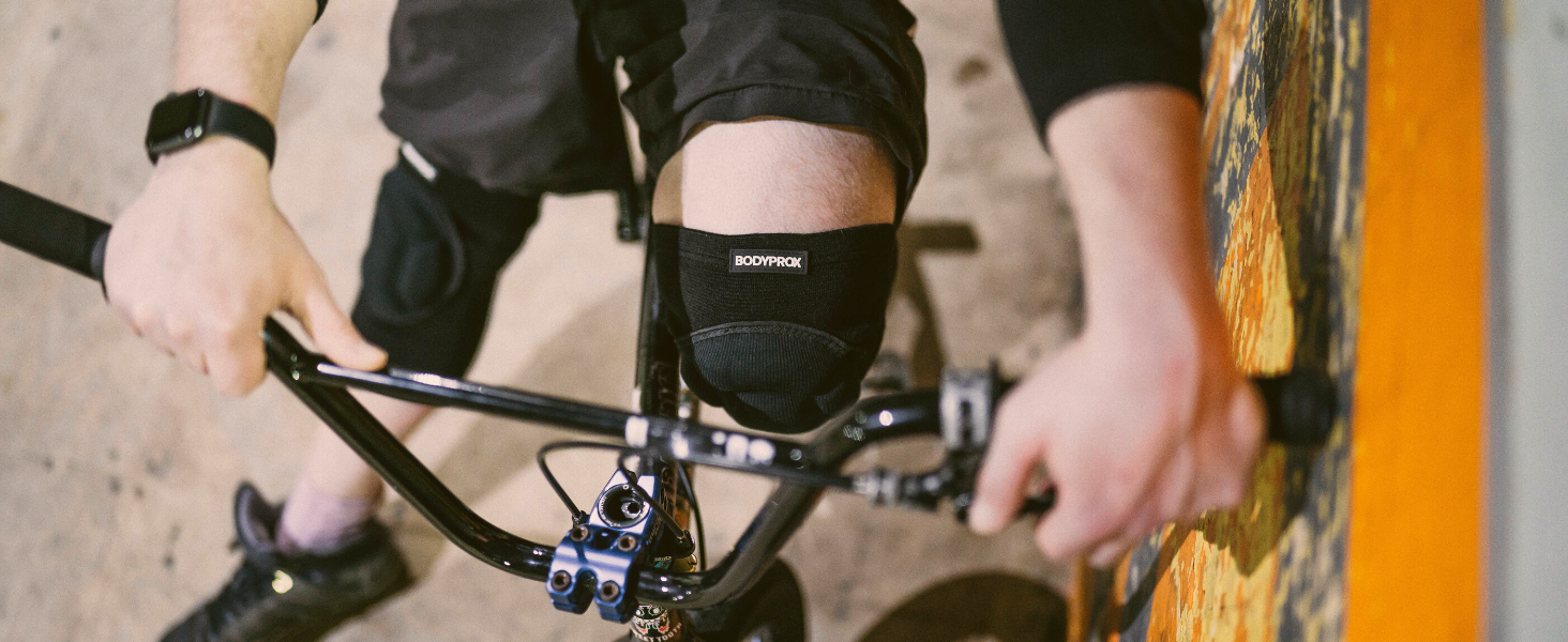 Man sitting on a bmx bike with close up of BODYPROX Knee Pads