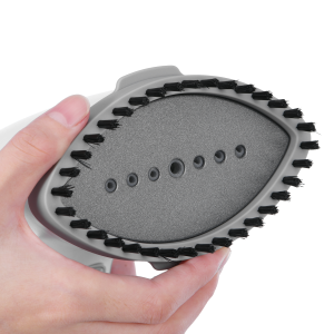 Hand holding a circular metal object with a textured surface. The item has a serrated edge and small holes in the center area.