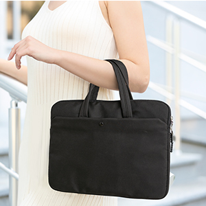 Black laptop bag with handles held by a person. Sleek, slim design suitable for carrying electronic devices.