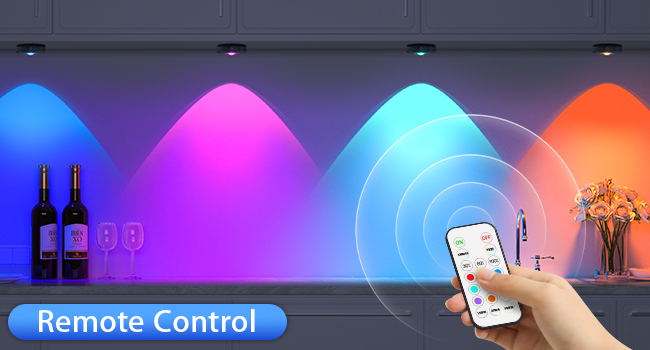 Colorful LED lighting system with remote control. Four light cones in blue, pink, cyan, and orange illuminate a kitchen counter with wine bottles.