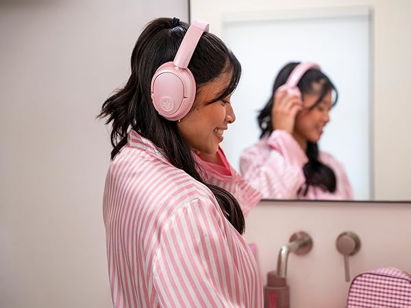 Woman doing her makeup while wearing jlab headphones