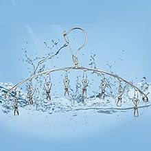 Metal clothes hanger with clips splashing through water against light blue background, creating dynamic water droplet effect.