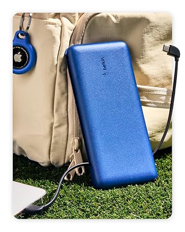 Image of belkin portable charger power bank next to backpack and phone on grass.