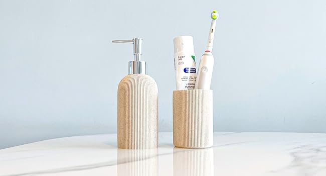 sand beige soap dispenser and toothbrush holder on the marble table