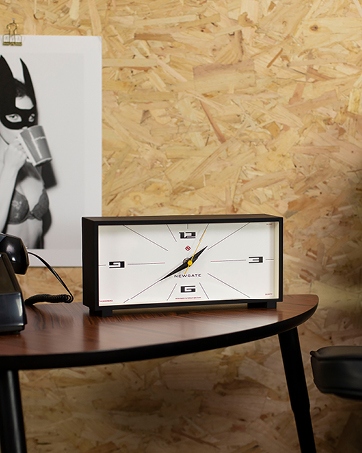 a clock on a table next to a phone.