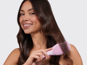 A woman brushing her hair with a pink ultimate detangler brush.