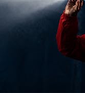 Person wearing deep red or maroon jacket against dark blue water background. Upper body visible showing outerwear in outdoor setting.