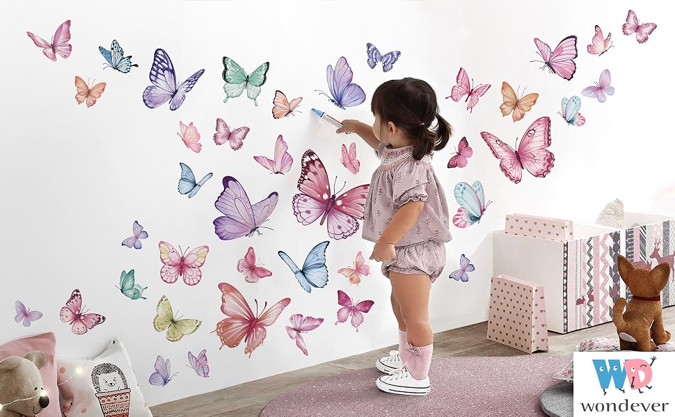 Text reads 'wonderscr'. Decorative butterfly wall decals in pastel colors of pink, blue, purple, and green arranged along a white wall, with application demonstration shown in sequence.
