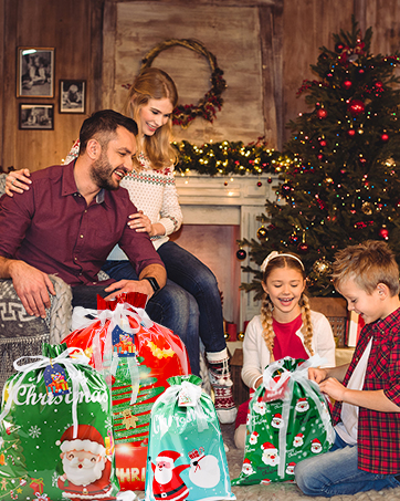 Family in festive room with Christmas tree. Adults and children opening colorful gift bags with holiday designs.