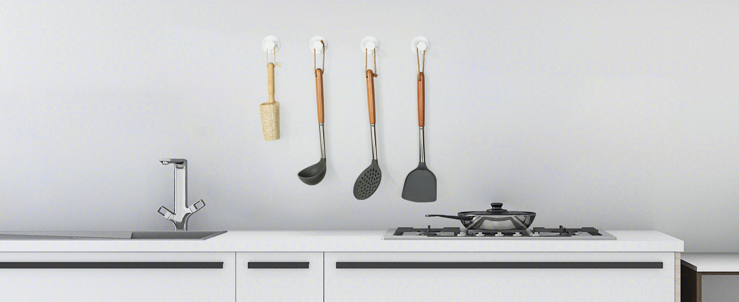 Modern white kitchen countertop with mounted faucet and cooktop, displaying four hanging kitchen utensils including spoons and spatulas.