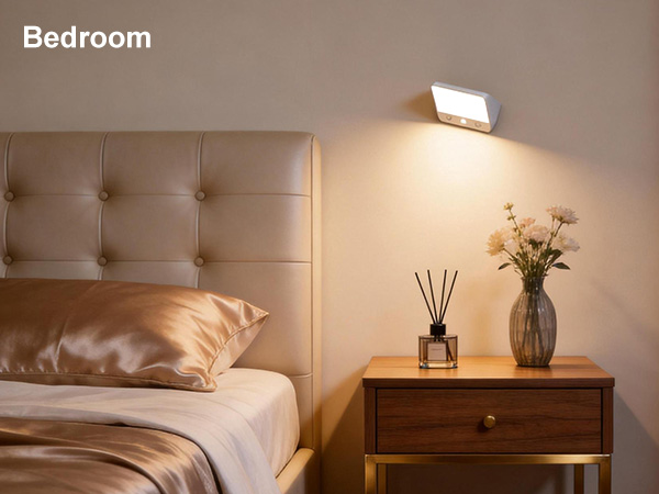 Text reads 'Bedroom'. Minimalist bedroom interior with white upholstered headboard, wooden nightstand, warm lighting, and decorative vase with flowers.
