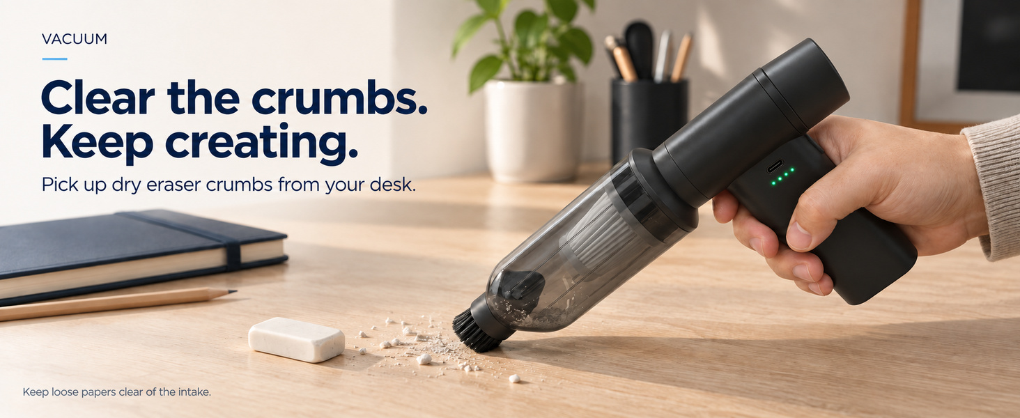 Mini desk vacuum picking up dry eraser crumbs from a wooden desktop with a brush attachment