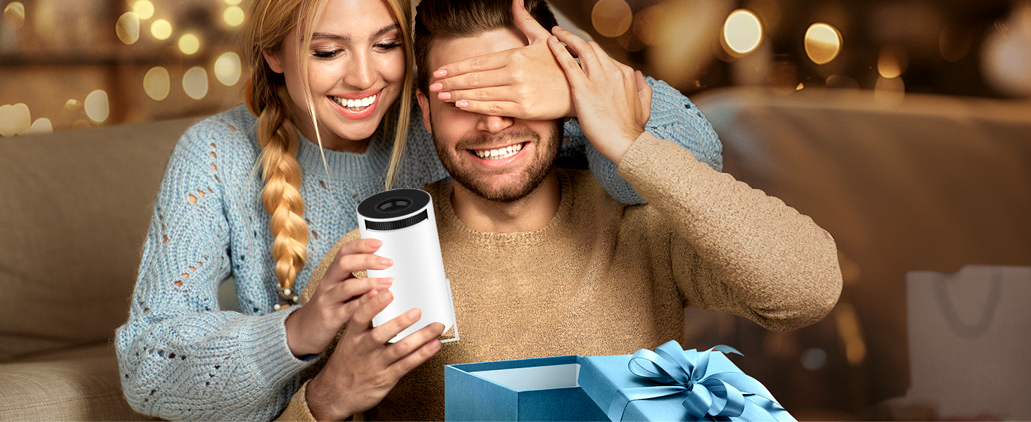 Two people sitting together, one holding a white cup. Blurred background with warm lighting and a gift box visible.