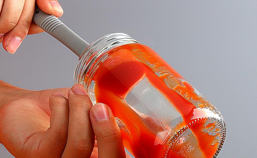 A silicone spatula with curved edge is used to scrape a jar with tomato sauce left