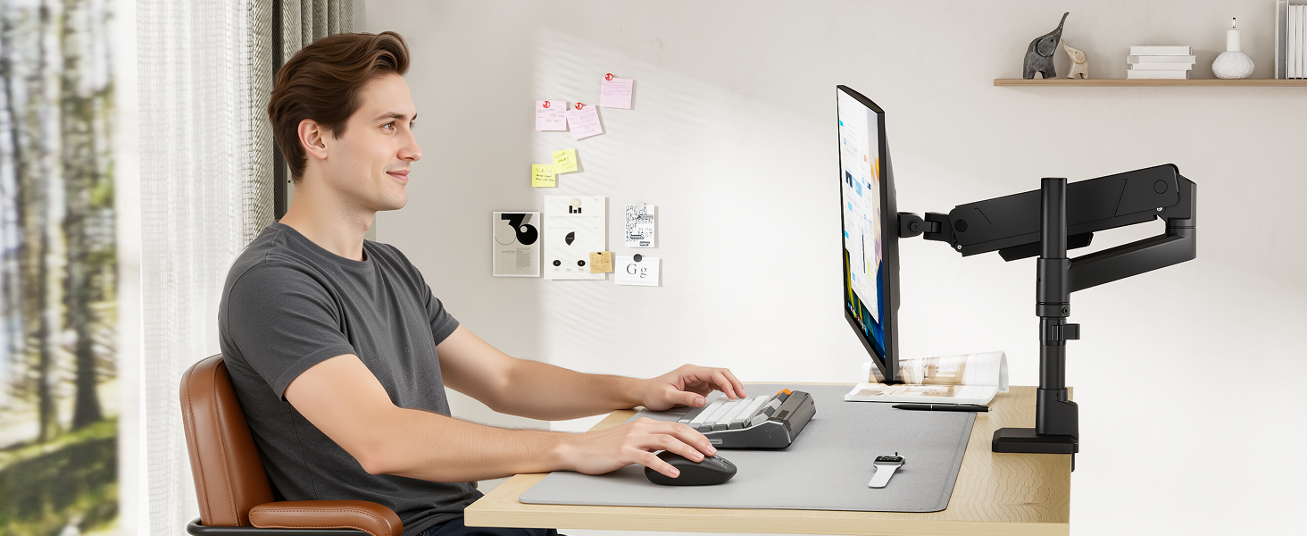 Man at desk in home office setting using adjustable black desk-mounted microphone arm while working on computer.
