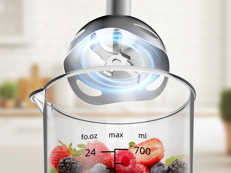 Clear food processor or blender container with measurement markings up to 700ml, shown with fresh berries inside and a transparent lid with pouring spout.
