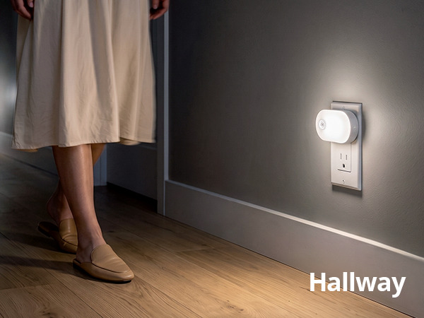 Plug-in night lights guiding a person walking down a hallway.