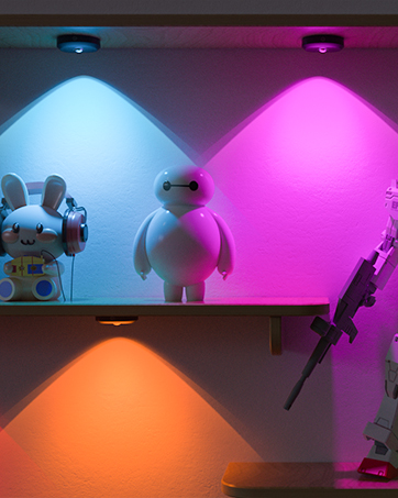 Three colored LED lights illuminating figurines on a shelf. Blue, pink, and orange lights create distinct color zones.