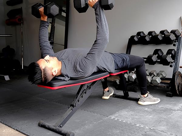 man doing bench press in home gym with weights and exercise mat gym flooring