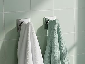 Bathroom wall with mint green tiles displaying hanging mint green and white towels in an organized row.