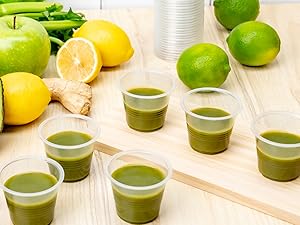 Green wellness shots in small clear plastic cups.