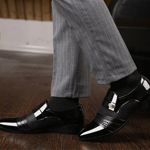 man wearing leather shoes freshly polished with boot polish applicator and buff brush