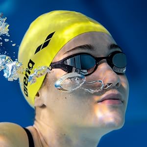 woman wearing a yellow arena swim cap and arena swim goggles under water in a pool