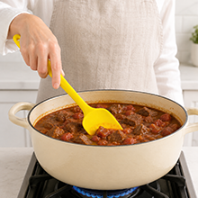 yellow silicone spatula stirring food in pot
