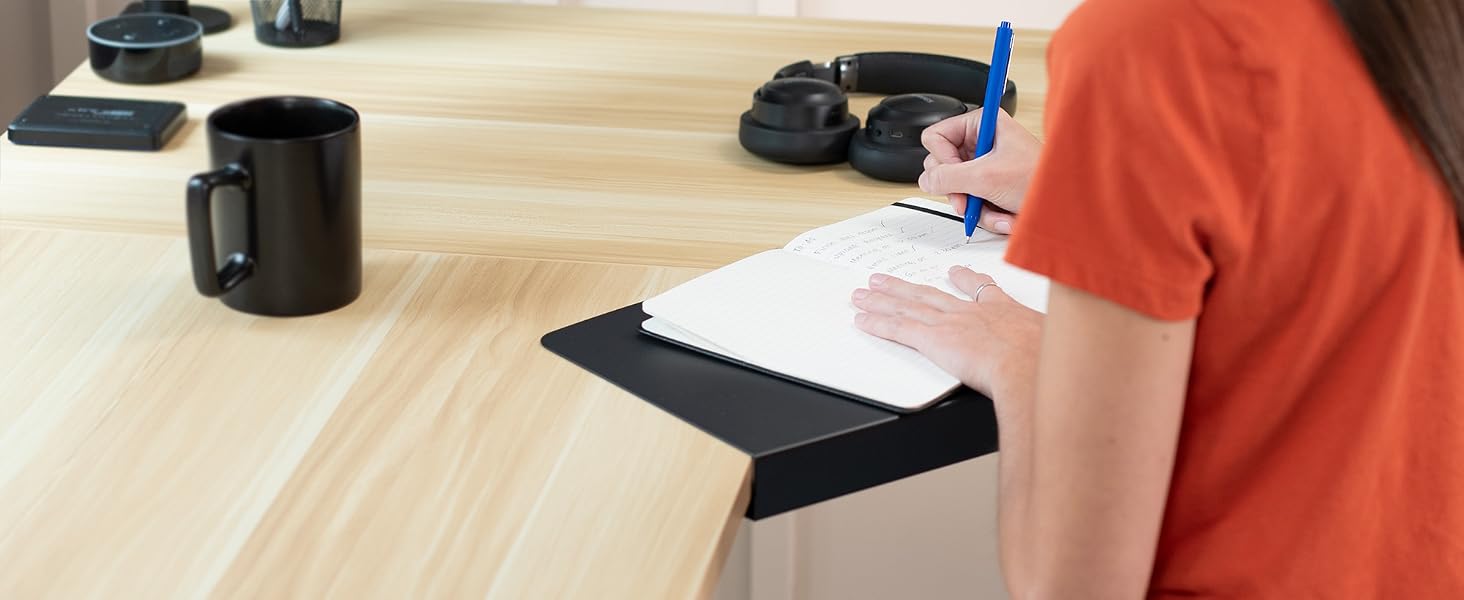 woman writing in notepad on corner desk