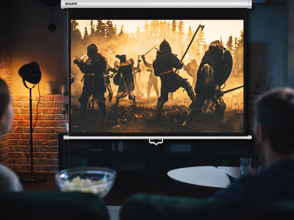 Projector screen displaying a medieval battle scene with silhouetted warriors in a misty forest. Visible in foreground: part of a table with a bowl and audience members.
