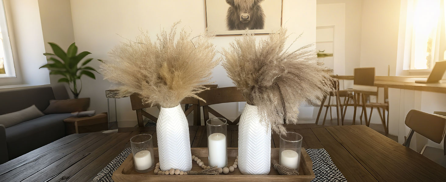 Two white rippled ceramic vases with pampas grass, candle holders and wooden tray, natural and cozy.