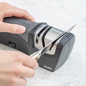 pocket knife being sharpening in handheld electric knife sharpener electric plug in