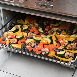 Veggies being cooked inside toaster oven using mesh mat